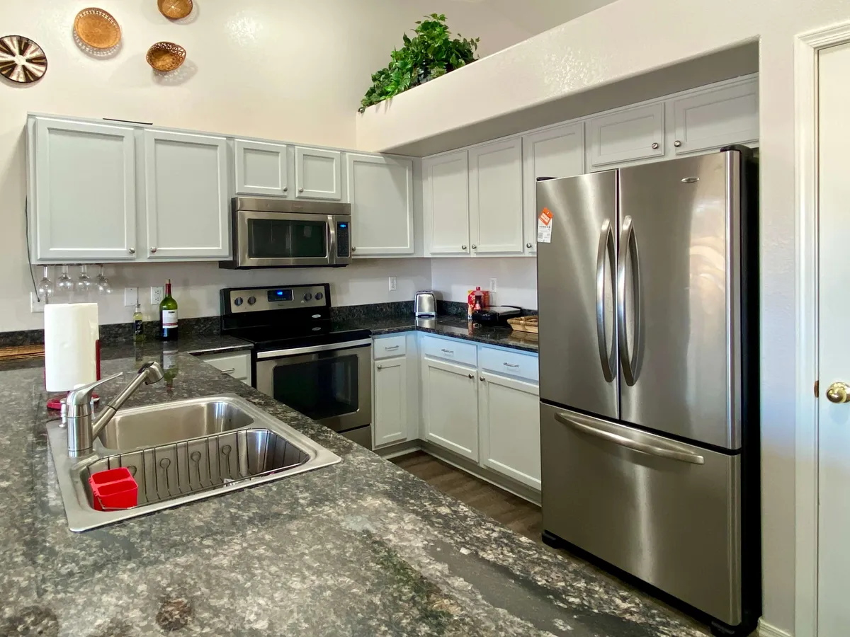 A bright, modern kitchen with granite countertops, stainless steel appliances, and white cabinetry. The open layout invites shared meals and gatherings, ideal for hosting dinner parties or brunch after a day out.