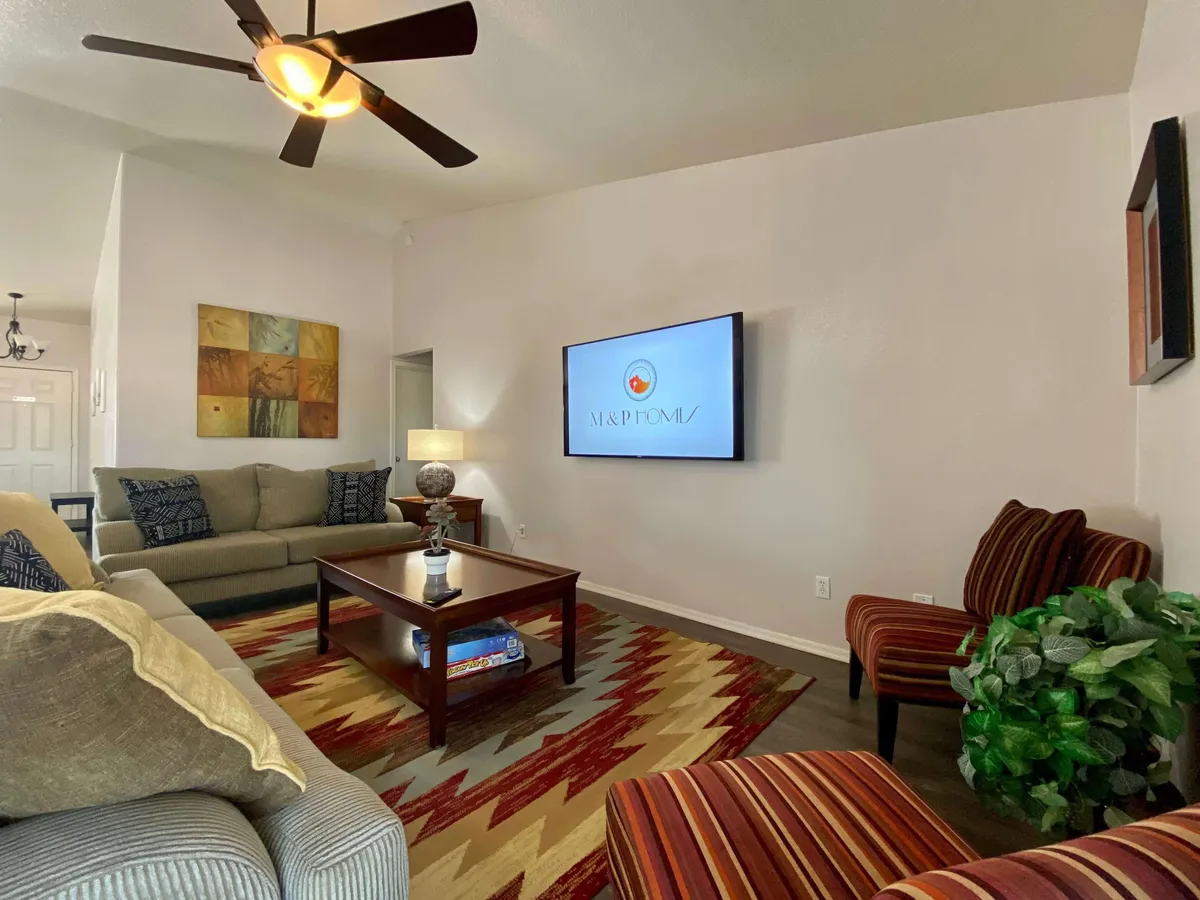 A comfortable and spacious living room featuring a plush sofa, a modern coffee table, and a large flat-screen television. The surrounding artwork and décor foster a relaxed ambiance perfect for family gatherings or quiet evenings. The open layout hints at a seamless flow to adjacent areas, ideal for hosting game nights or watching TV together.